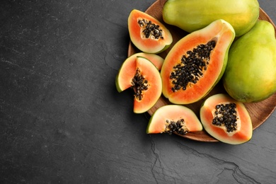 Fresh ripe papaya fruits on black background, flat lay. Space for text