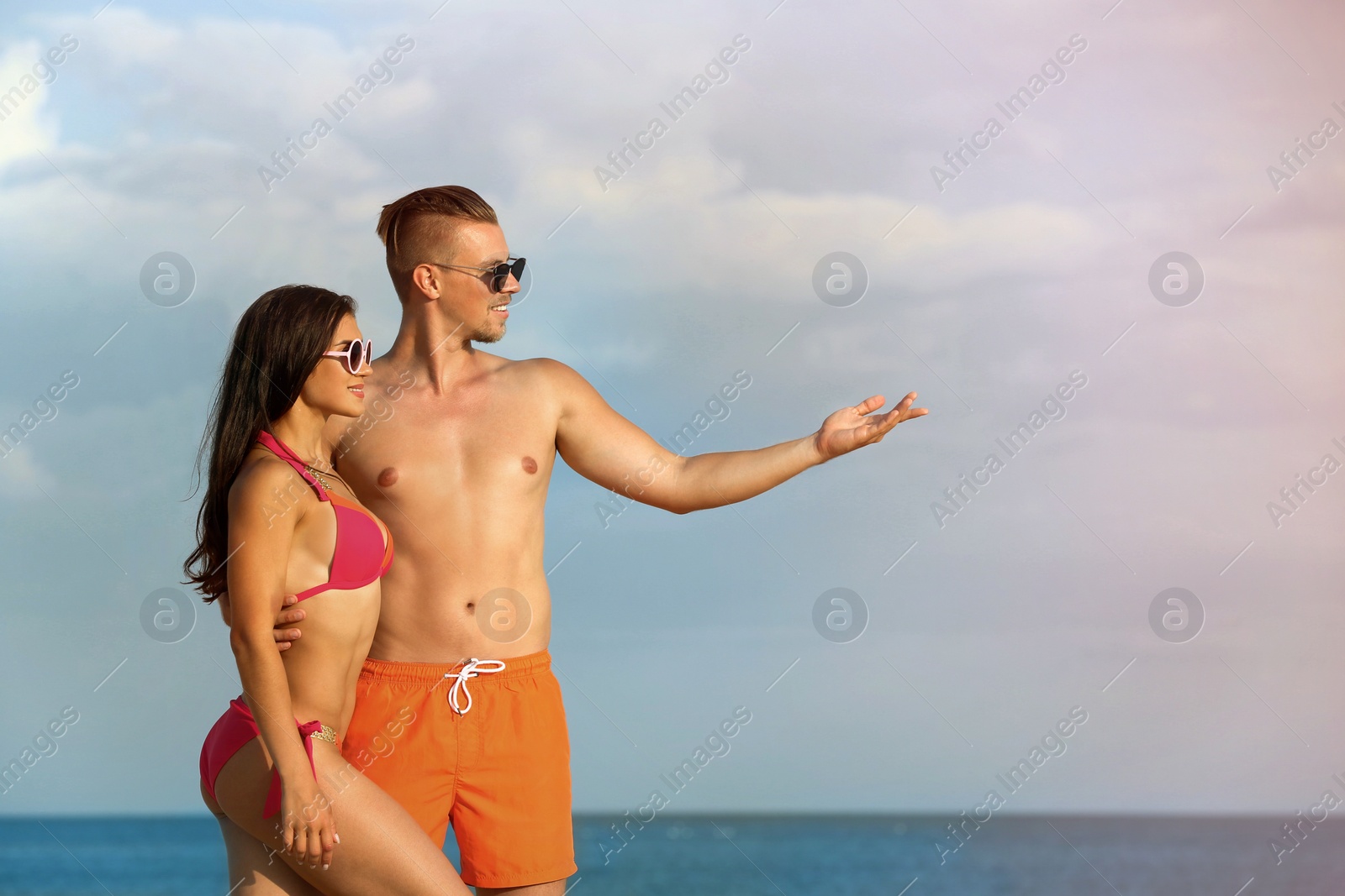 Photo of Young woman in bikini spending time with her boyfriend on beach. Lovely couple