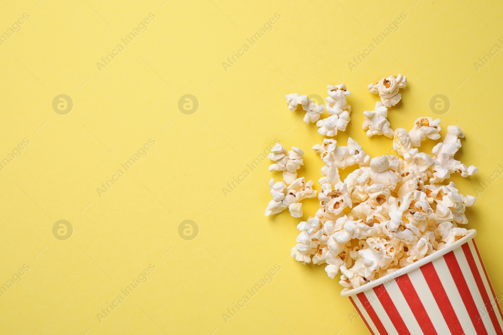 Photo of Delicious popcorn on yellow background, top view. Space for text