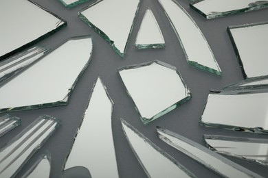 Photo of Shards of broken mirror on grey background, closeup
