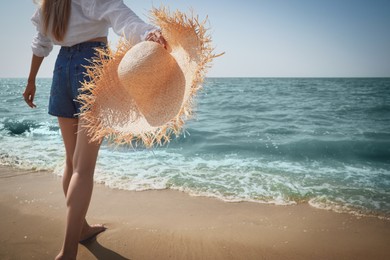 Photo of Young woman with straw hat near sea on sunny day in summer, closeup