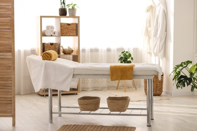 Comfortable massage table with clean towels in spa center