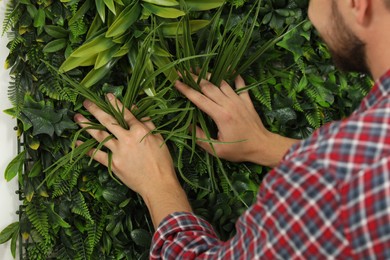 Man installing green artificial plant wall panel, closeup