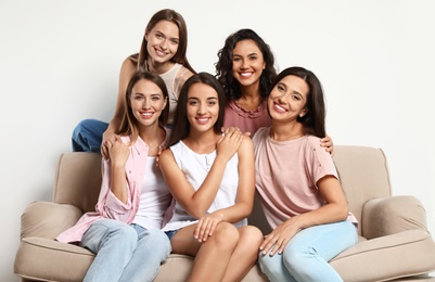 Happy women sitting on sofa near white wall. Girl power concept