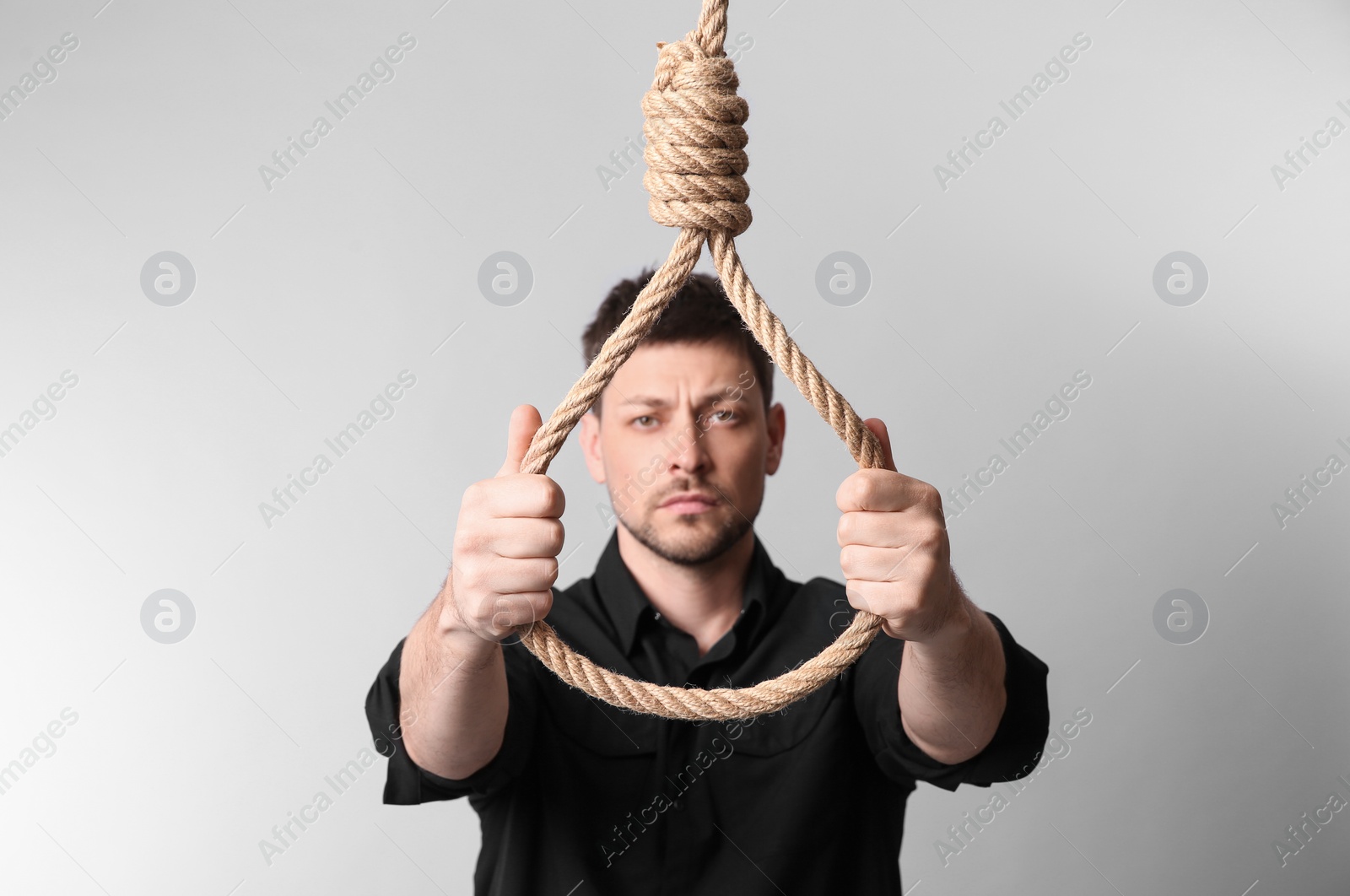 Photo of Depressed man with rope noose on light background