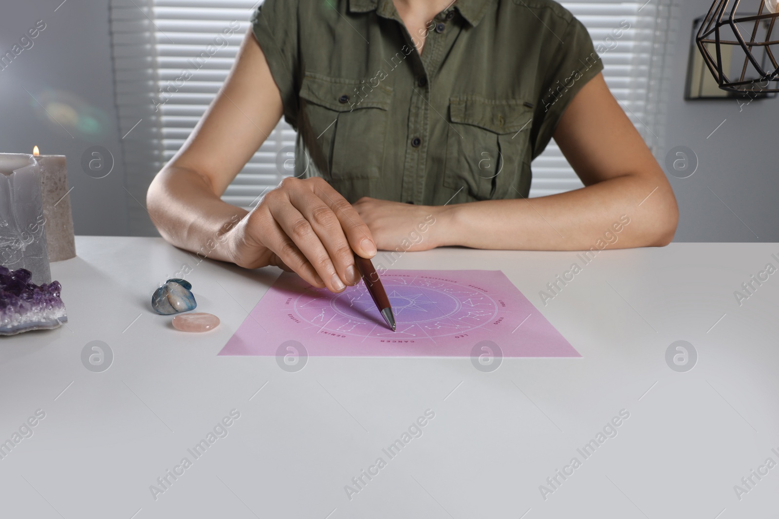 Photo of Astrologer predicting future with zodiac wheel at table indoors, closeup