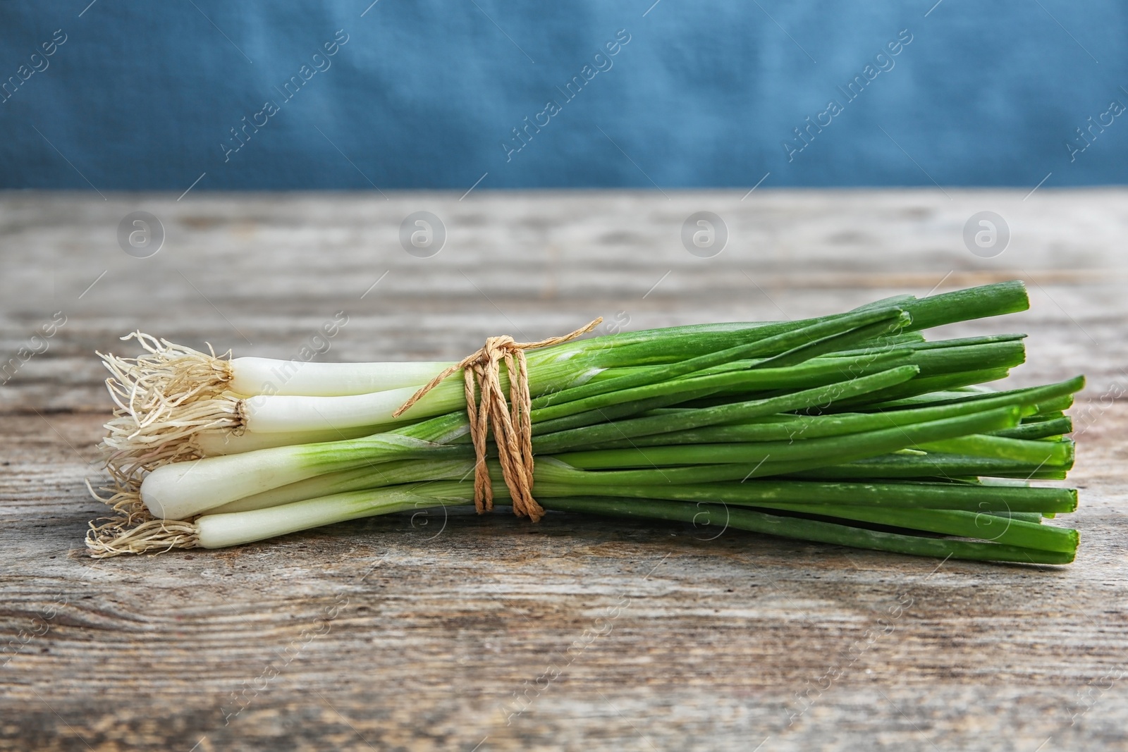 Photo of Tied fresh green onion on wooden table