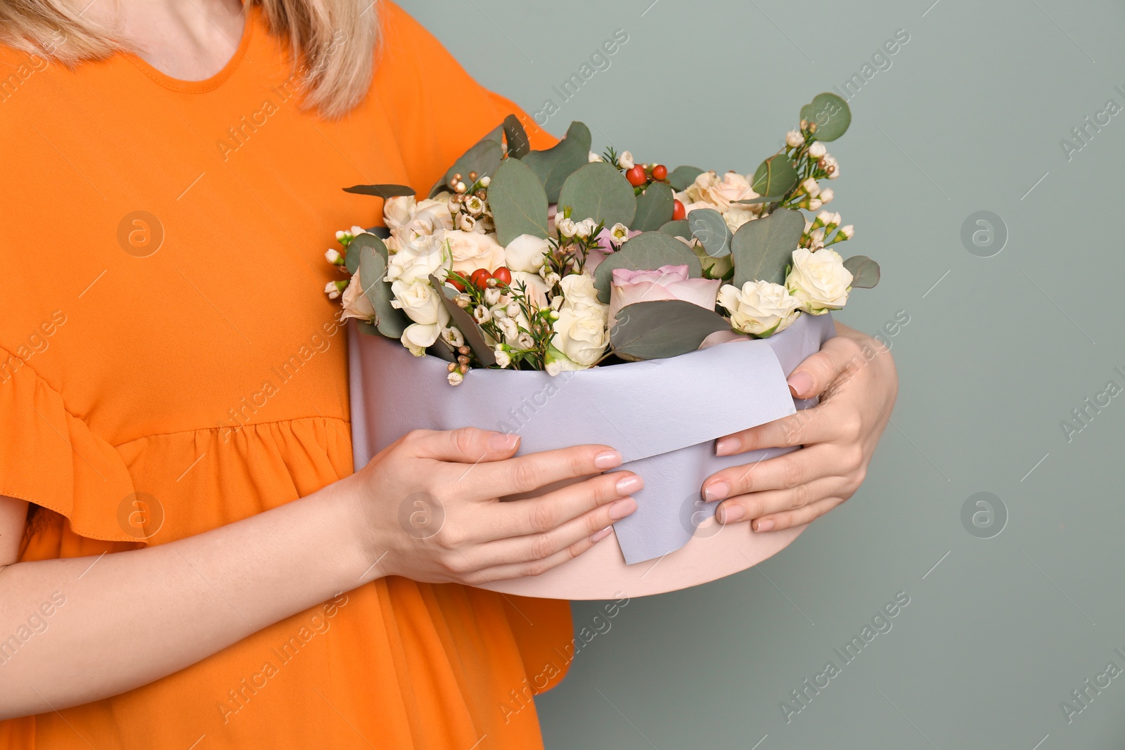 Photo of Female florist holding box with flowers on grey background