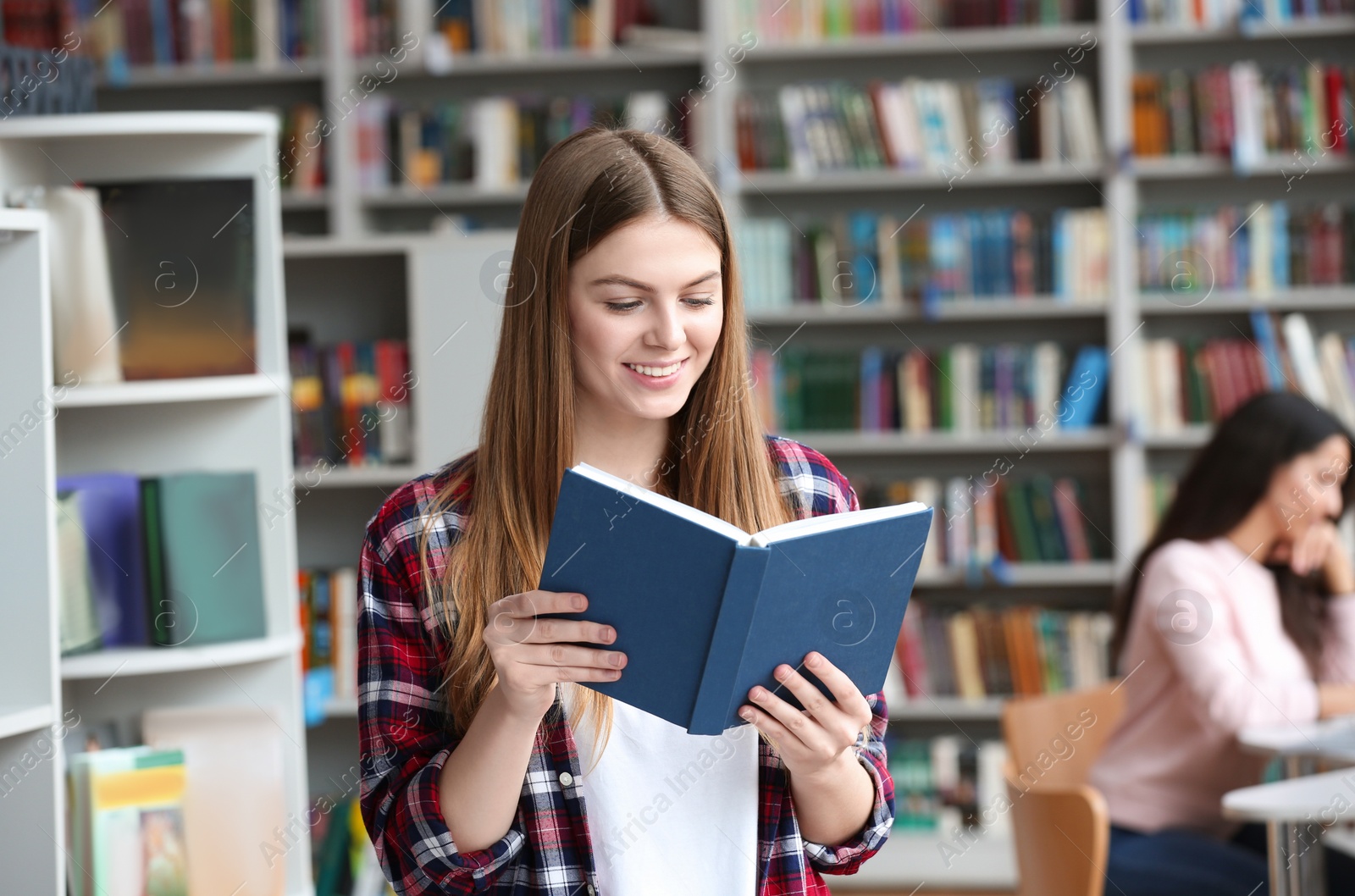 Photo of Young pretty woman reading book in library