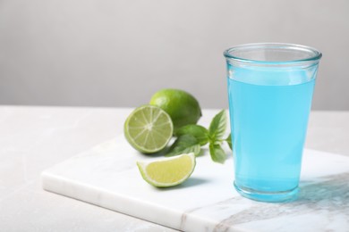 Refreshing light blue drink on white table, space for text