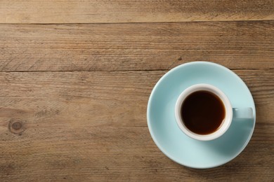 Photo of Tasty coffee in cup on wooden table, top view. Space for text