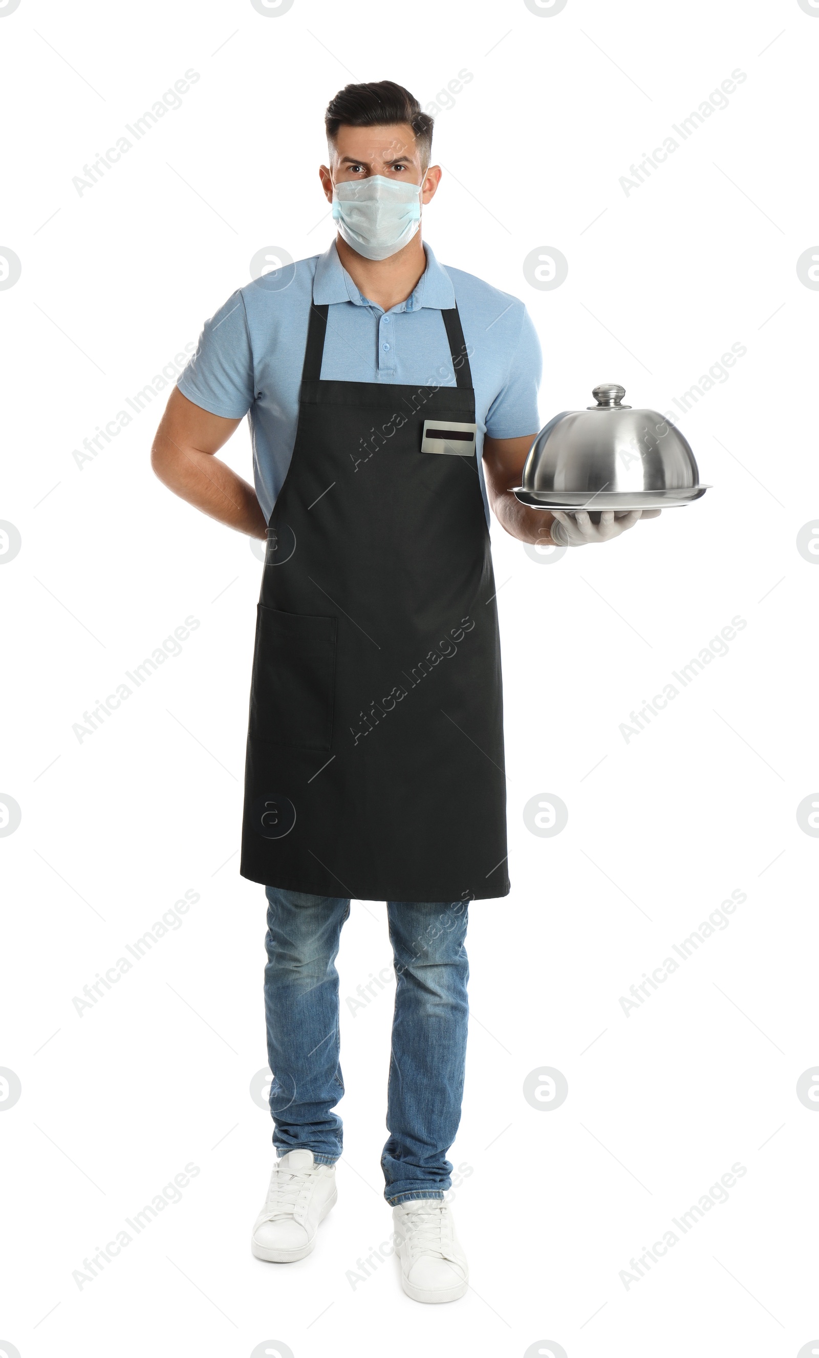 Photo of Waiter in medical face mask holding tray with lid on white background