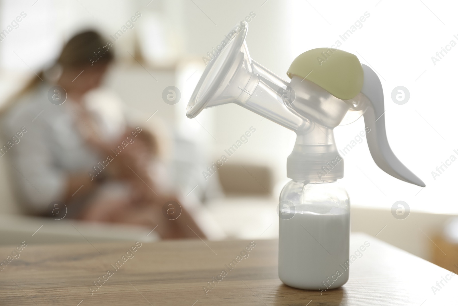 Photo of Mother feeding her little baby at home, focus on breast pump with milk. Healthy growth