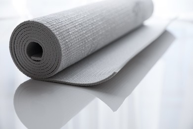 Photo of Rolled karemat or fitness mat on tiled floor, closeup