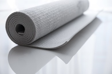 Rolled karemat or fitness mat on tiled floor, closeup