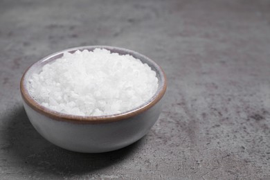 Photo of Bowl with white sea salt on grey table, space for text