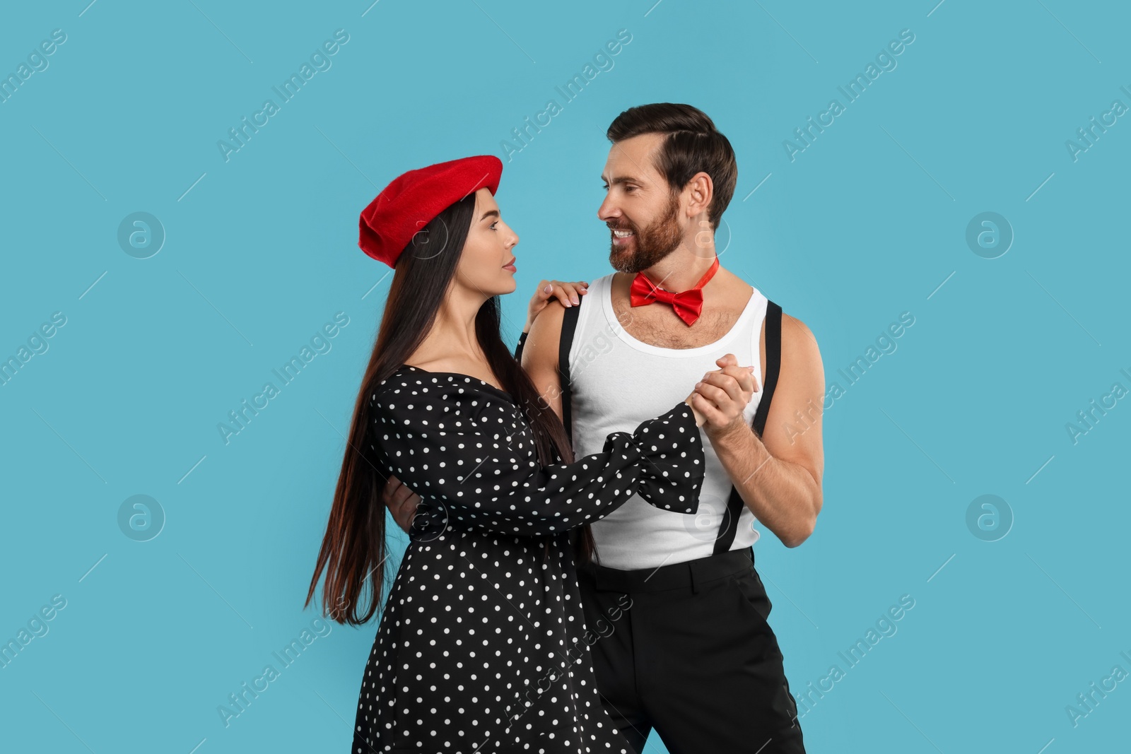 Photo of Happy couple dancing together on light blue background