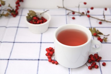 Photo of Cup with hawthorn tea and berries on table. Space for text