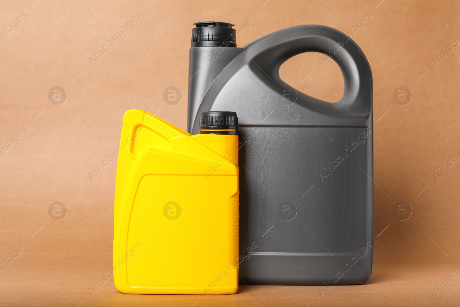 Photo of Motor oil in different canisters on light brown background