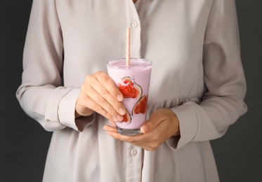 Woman holding fig smoothie on grey background, closeup