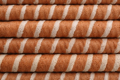 Tasty wafer roll sticks as background, top view. Crispy food