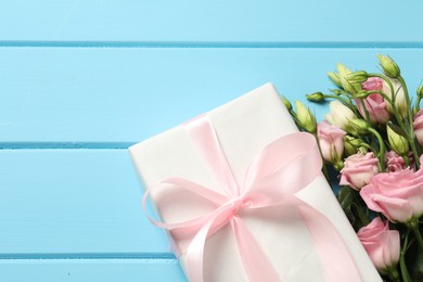 Happy Mother's Day. Beautiful flowers and gift box on light blue wooden table, flat lay. Space for text