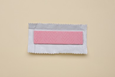 Unwrapped stick of tasty chewing gum on beige background, top view