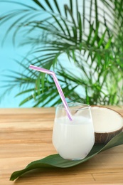 Composition with glass of coconut water on wooden table against blue background