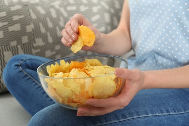 Photo of Woman eating chips while watching TV, closeup view