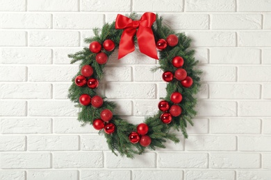 Photo of Beautiful Christmas wreath with festive decor on white brick wall