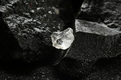 Shiny rough diamond on wet coal, closeup