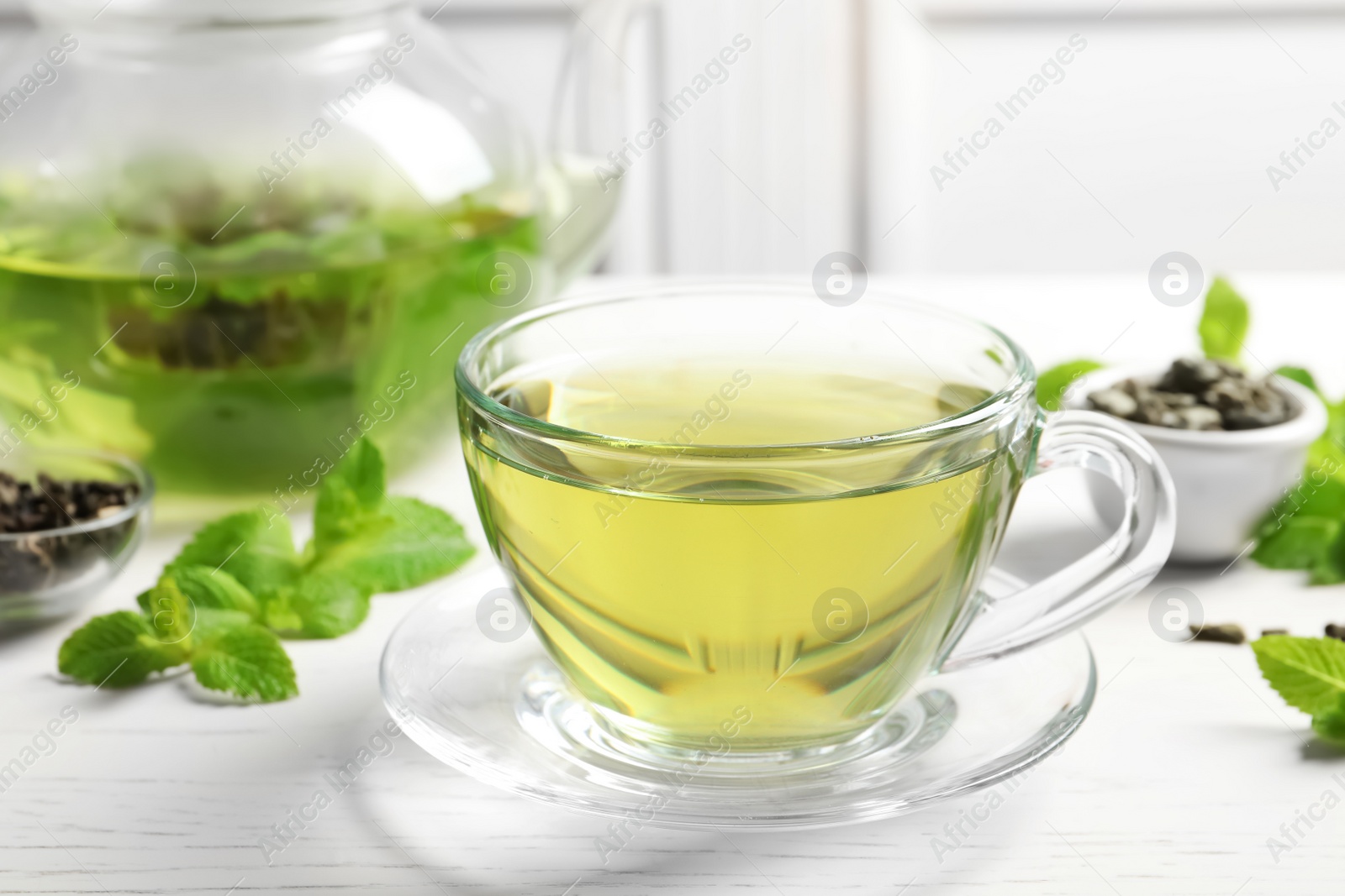 Photo of Cup with hot aromatic mint tea and fresh leaves on table