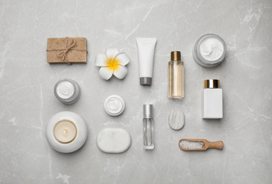 Flat lay composition with cosmetics and sea salt on grey marble table. Spa treatment