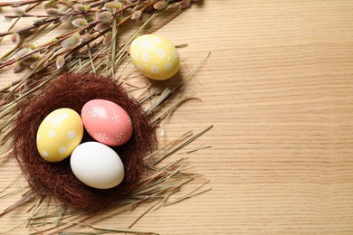 Photo of Flat lay composition with painted Easter eggs on wooden table, space for text