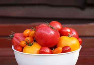 Bowl with fresh tomatoes on wooden surface, closeup