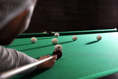 Photo of Young man playing Russian billiard indoors, closeup