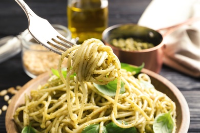 Fork with delicious basil pesto pasta over plate, closeup