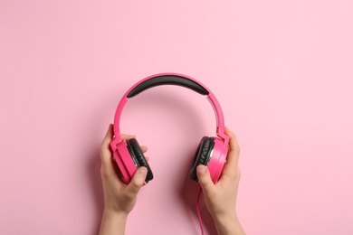 Woman holding stylish headphones on color background, closeup