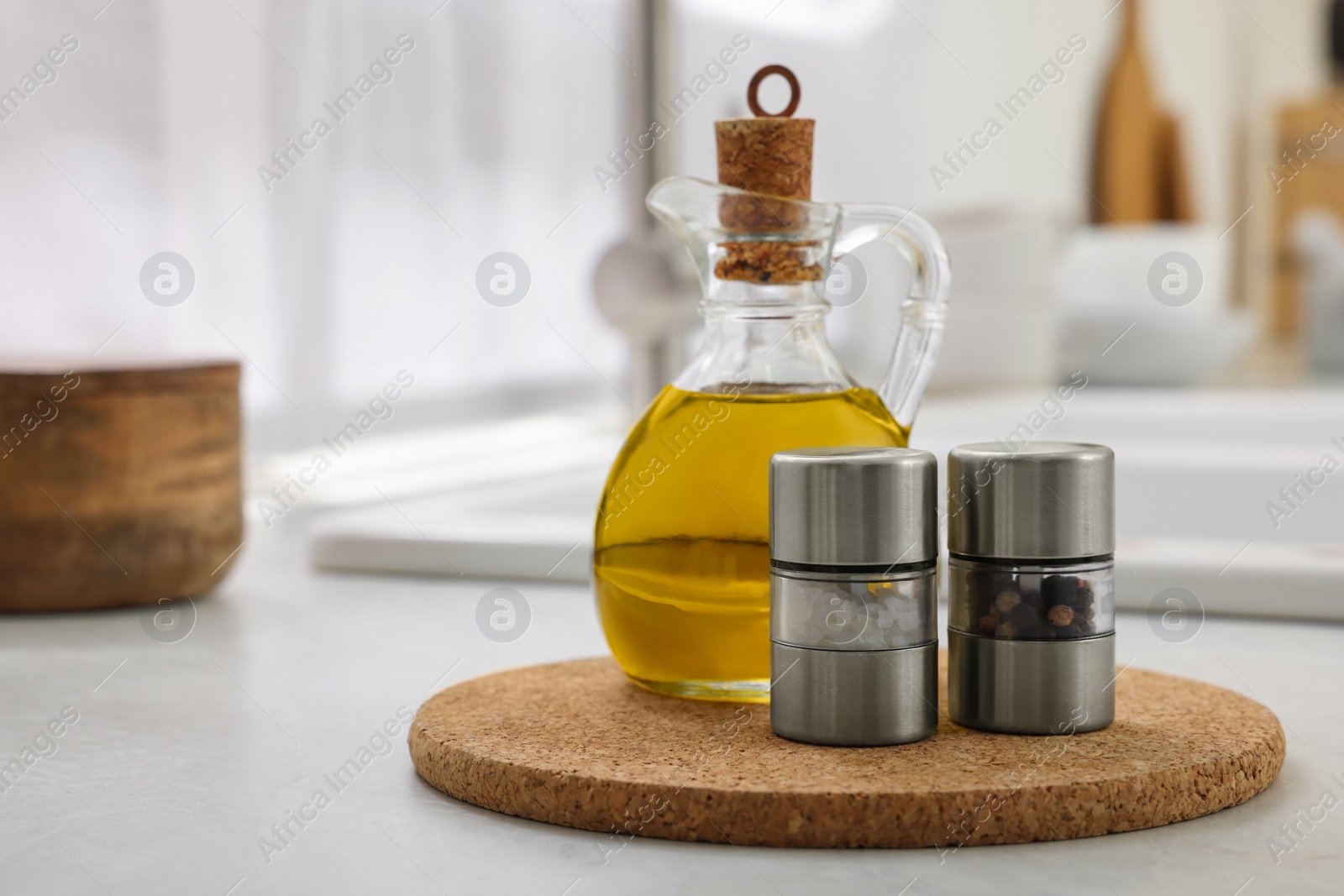 Photo of Salt and pepper mills with bottle of oil on table in kitchen. Space for text