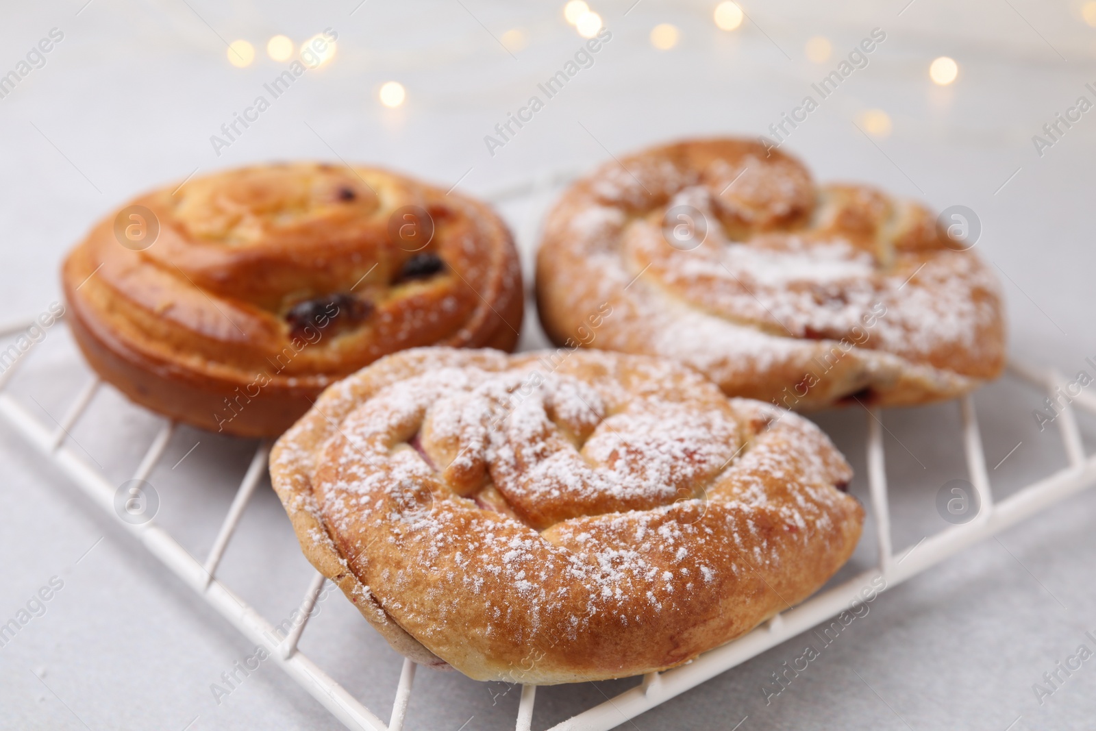 Photo of Delicious rolls with raisins and sugar powder on light table, closeup. Sweet buns