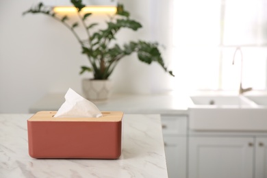 Photo of Box with paper tissues on white marble table in kitchen. Space for text