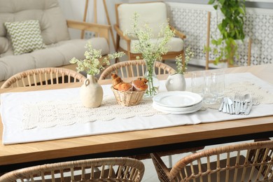 Photo of Clean dishes, flowers and fresh pastries on table in stylish dining room