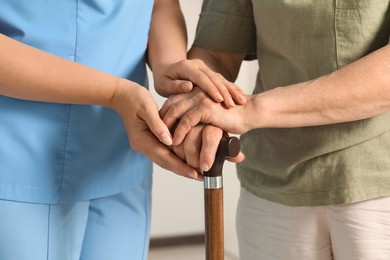 Photo of Elderly woman with walking cane and female caregiver indoors, closeup