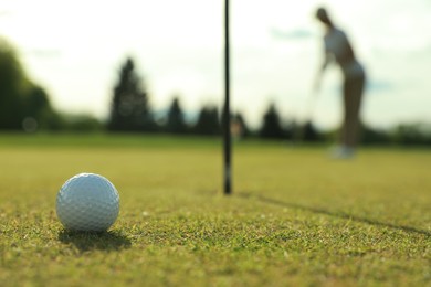 Photo of Woman playing golf at green course, focus on ball. Space for text