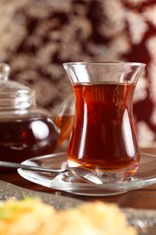 Photo of Traditional Turkish tea in glass on wooden table, closeup