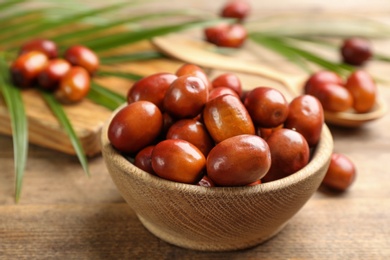 Photo of Palm oil fruits in bowl on wooden table, closeup