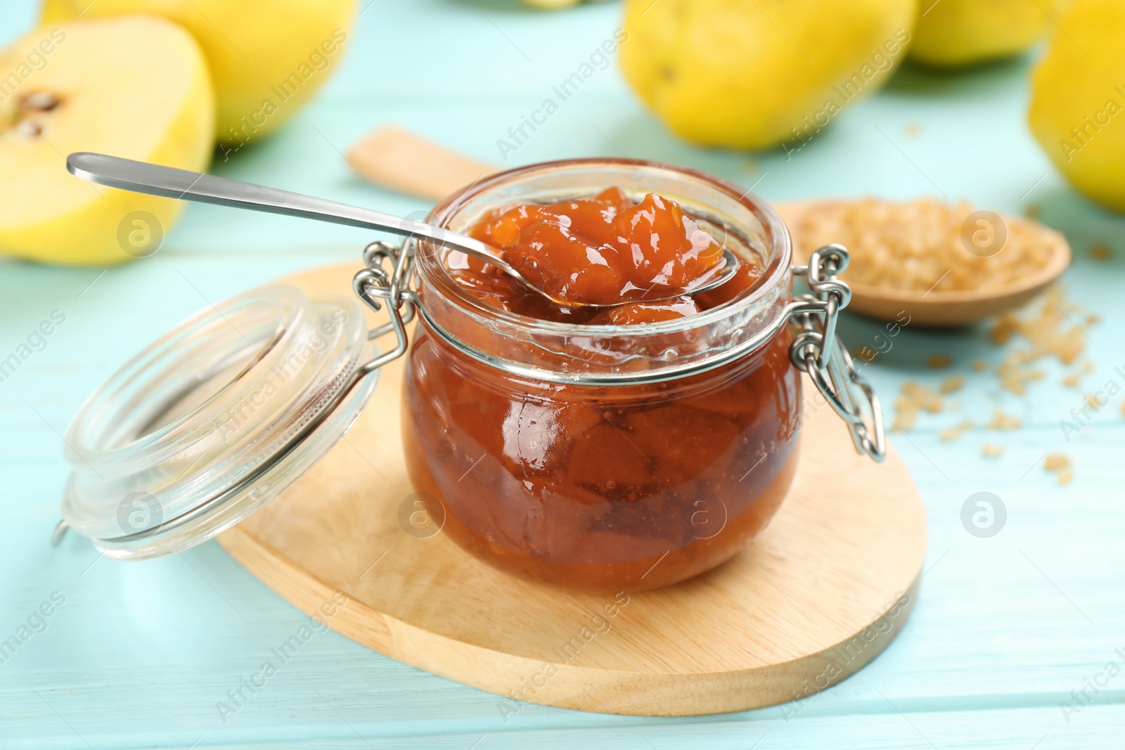 Photo of Delicious quince jam on light blue wooden table, closeup