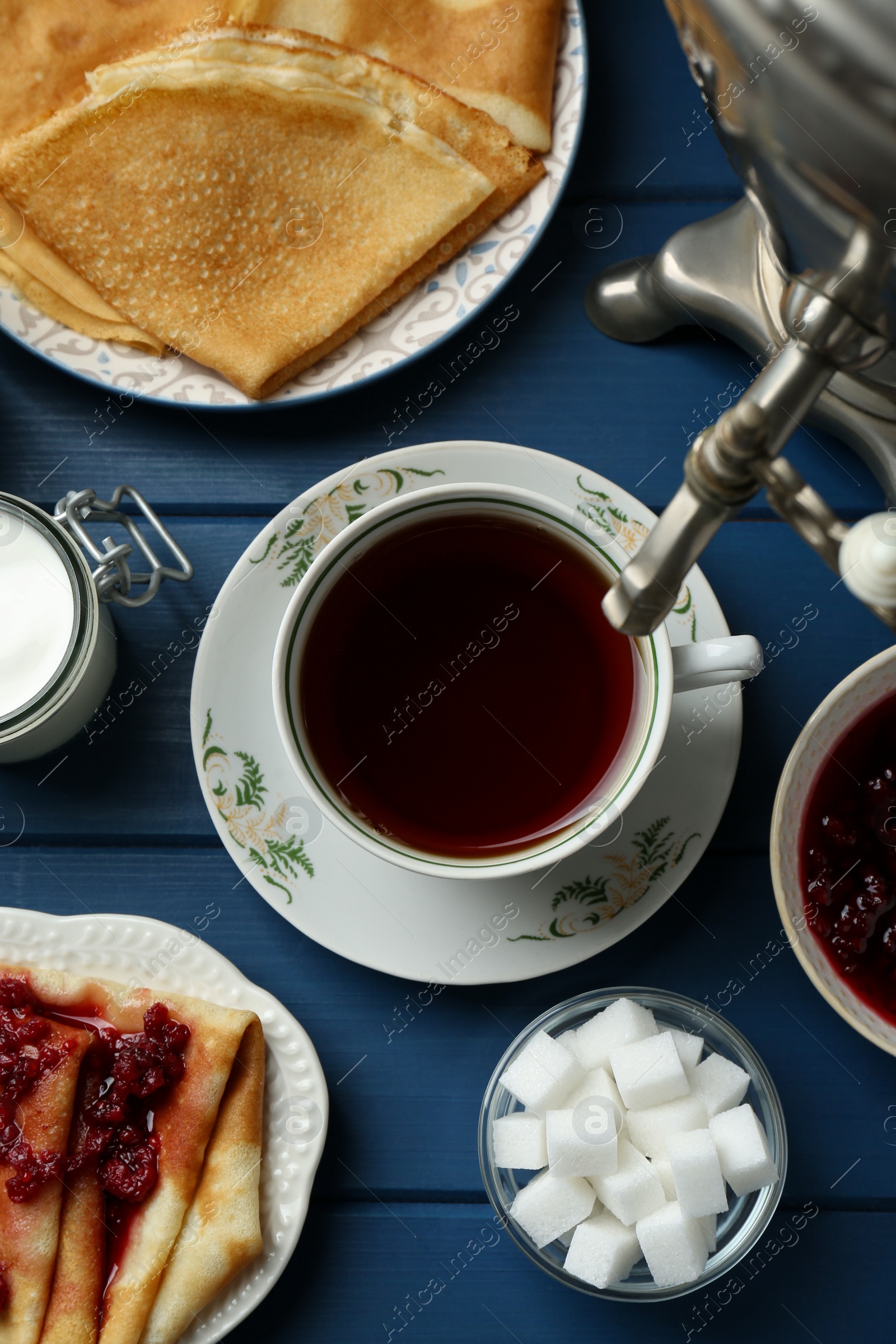 Photo of Aromatic tea, traditional Russian samovar and treats on light blue wooden table, flat lay