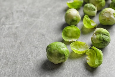 Photo of Fresh Brussels sprouts and leaves on table. Space for text