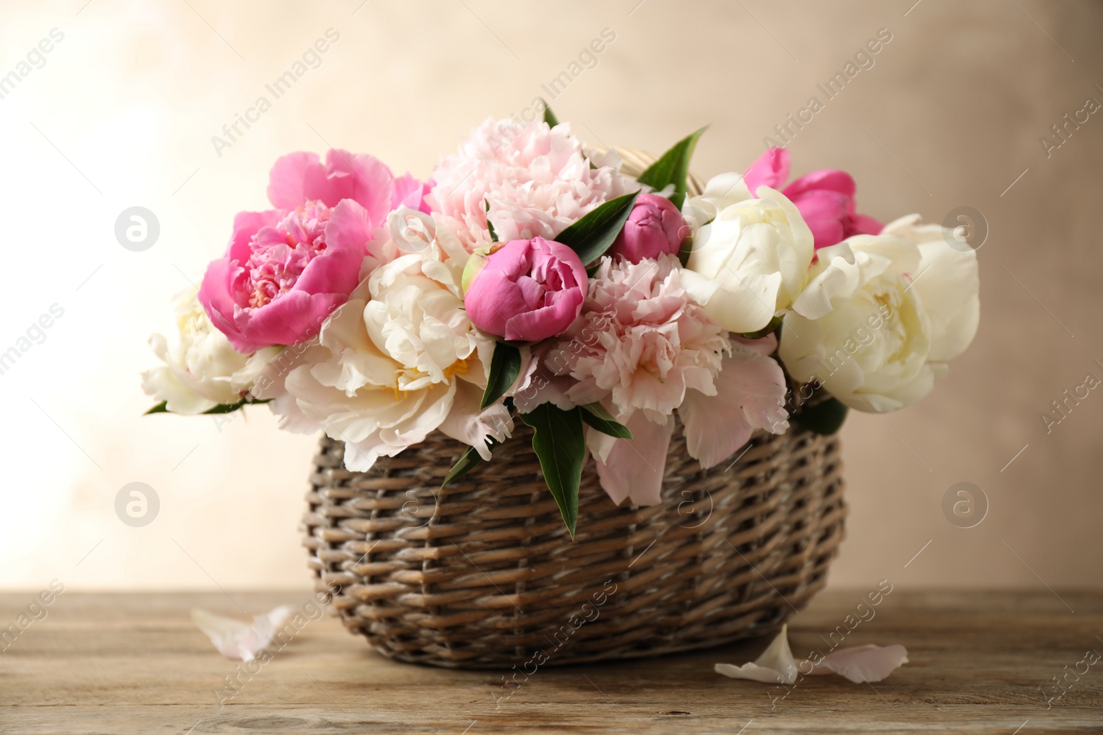 Photo of Beautiful peony bouquet in wicker basket on wooden table